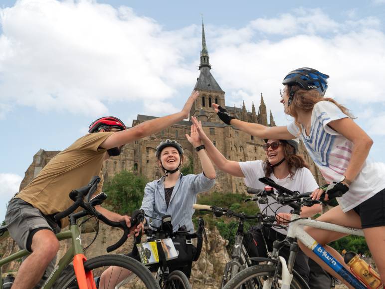 Cyclistes se tapant dans la main au pied du Mont Saint-Michel